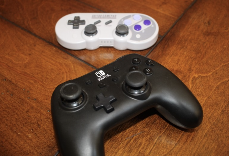 Two video game controllers positioned next to each other on a wooden table.