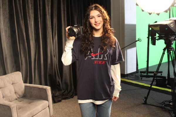 Lauryn Carr (25) posing with a camera in the T.V. and media production room 